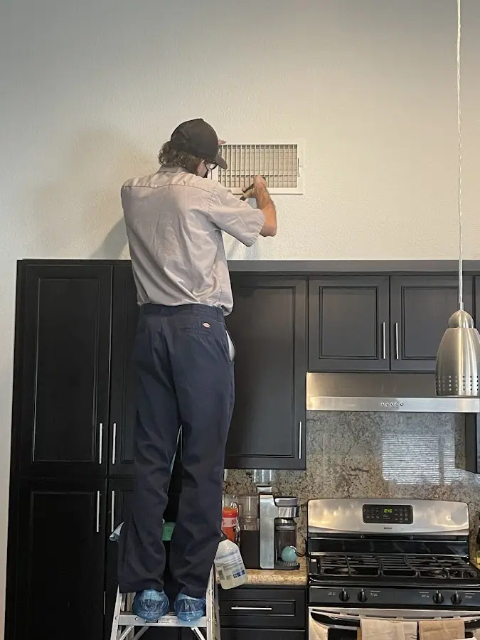 Technician inspecting an air vent during HVAC service in Cherry Hill